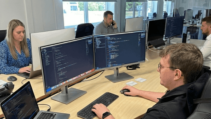 NYBE professionele I.T. in Hasselt custom software development kantoor medewerkers met focus op man in voorgrond werkend op computer die code toont